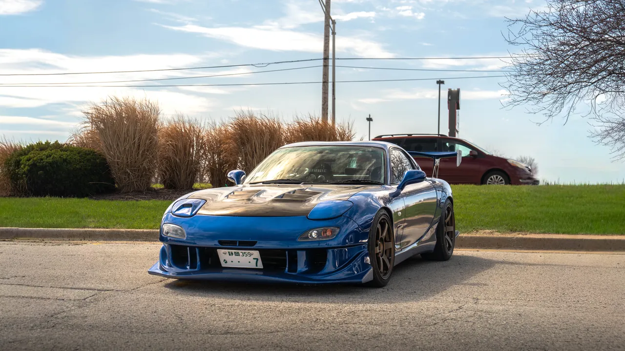 Blue Mazda RX-7 FD widebody parked at an angle in a sunlit lot