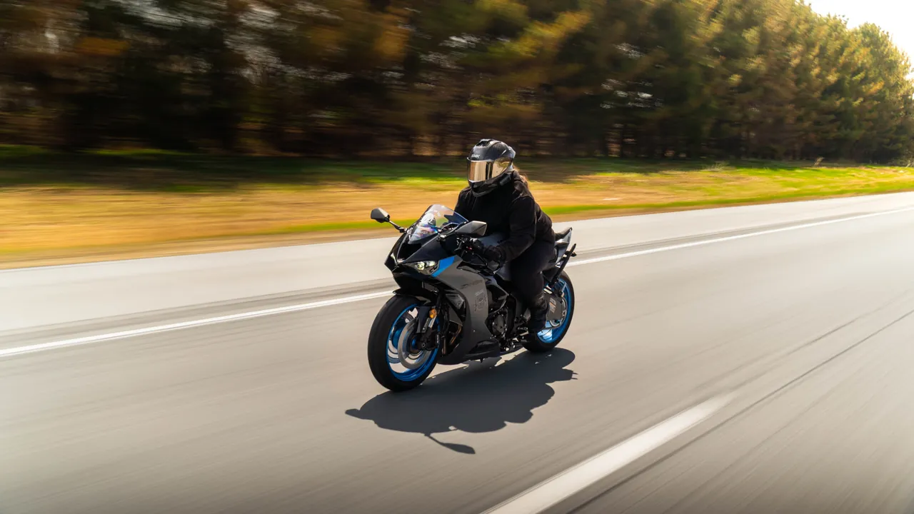 Rider on a sportbike captured in motion on an open highway past golden fields