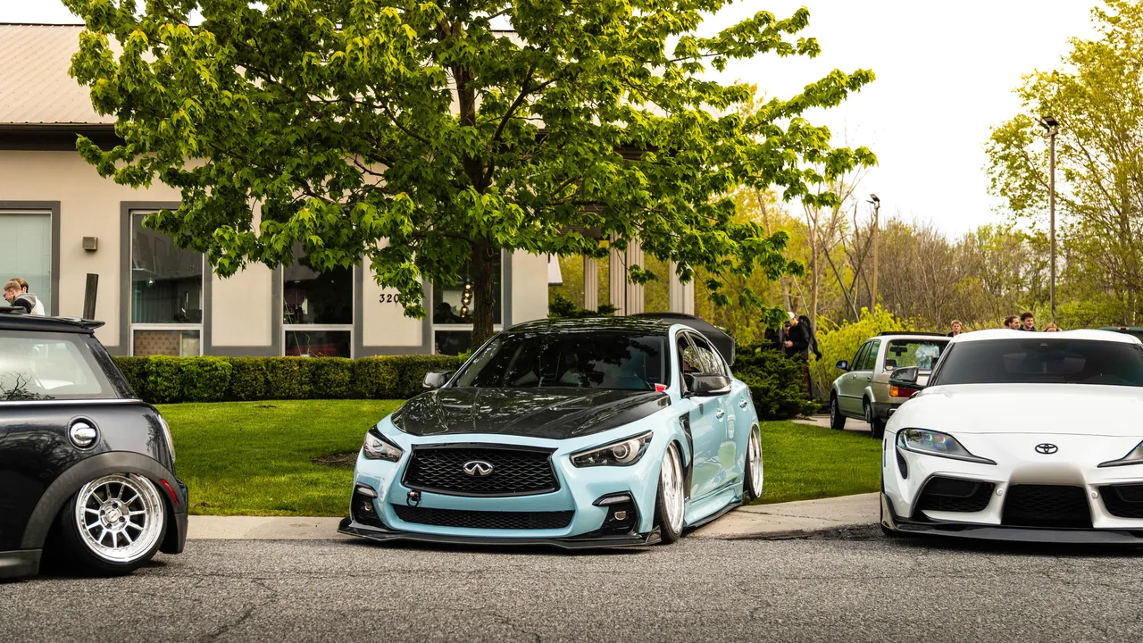 Teal bagged Infiniti Q50 sitting low among other cars at a spring meet